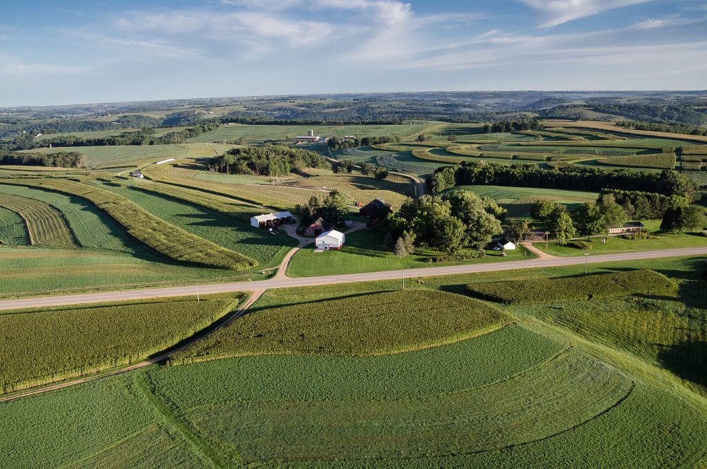 A rural landscape with a farm in the distance.